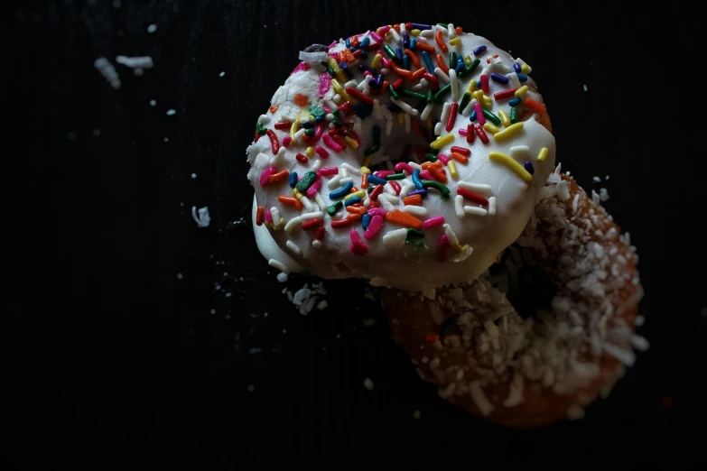 two donuts topped with white frosting and sprinkles