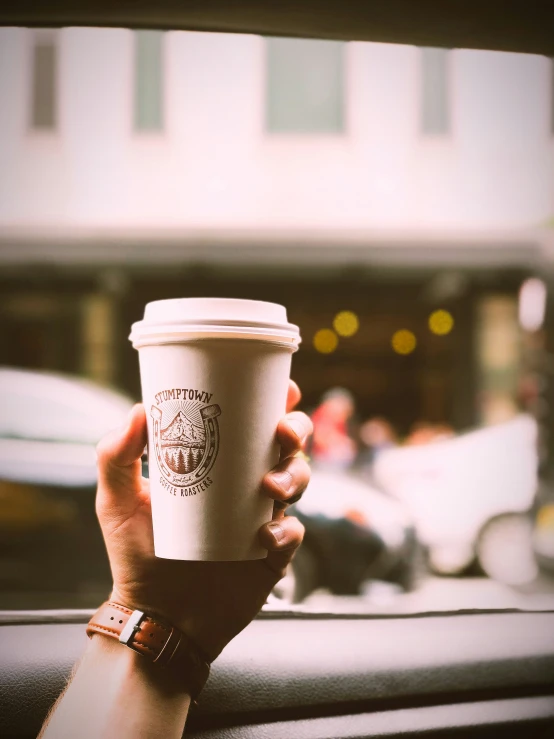 a hand holding up a cup with food on top