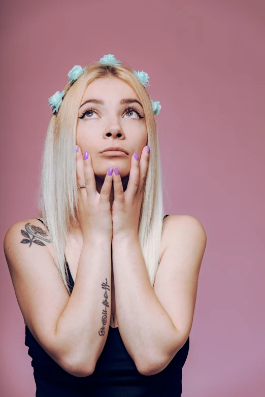 woman with blonde hair and blue nail polish holding her hands near the face