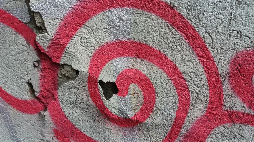 graffiti art on a cement wall with a red painted spiral