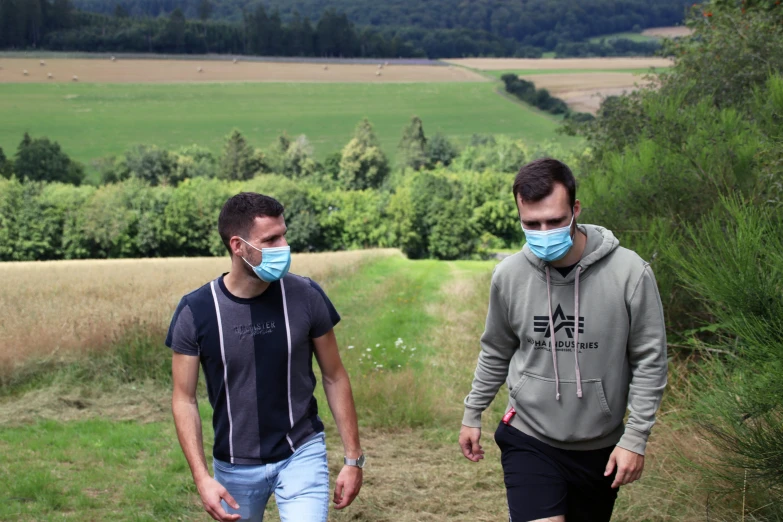 two men walking together and wearing masks on their faces