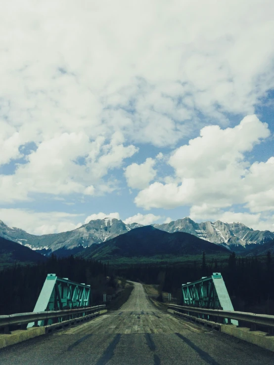 a truck passing over a bridge with mountains in the background