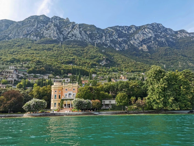 the shore line of a large lake and green mountains in the background