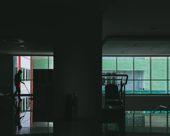 a dark room with a woman standing outside looking out of the window