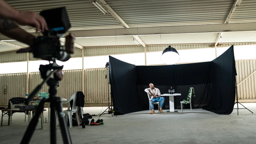 a pographer shoots an individual sitting on a chair with his camera