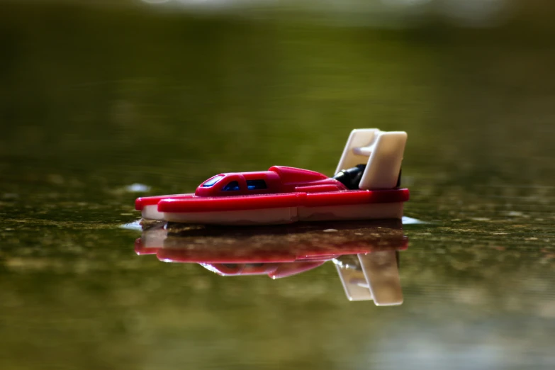 an miniature red toy boat on the water