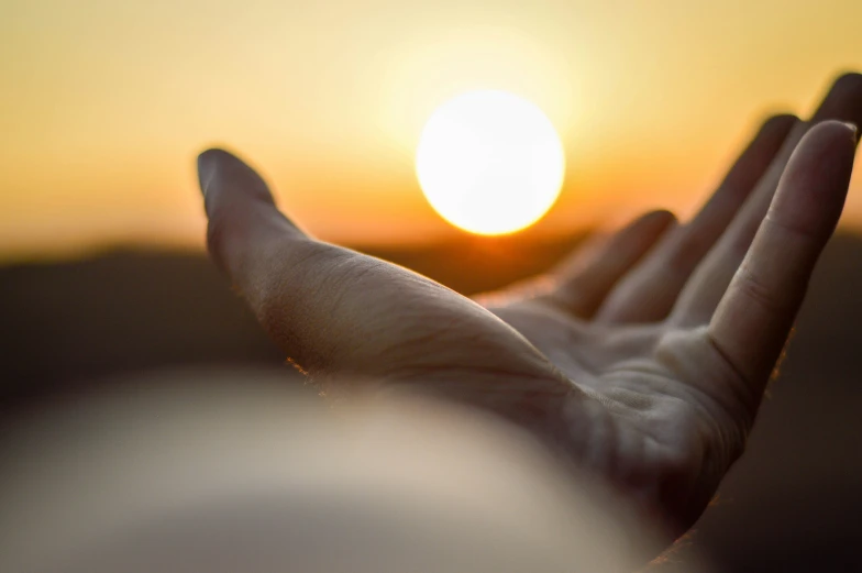 hands reaching for the setting sun with the hand outstretched