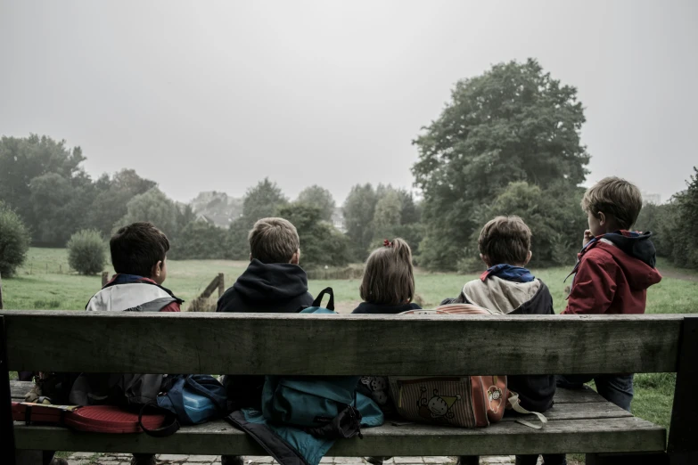 a group of children are sitting on a bench