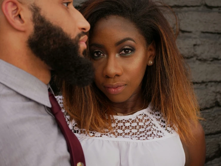 a man and woman standing next to each other with their eyes open