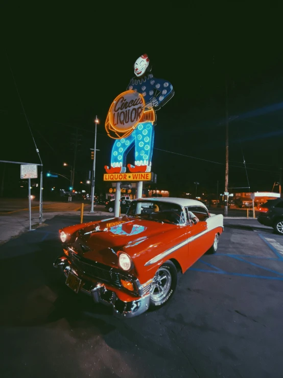 a old car is parked in front of an advertising sign