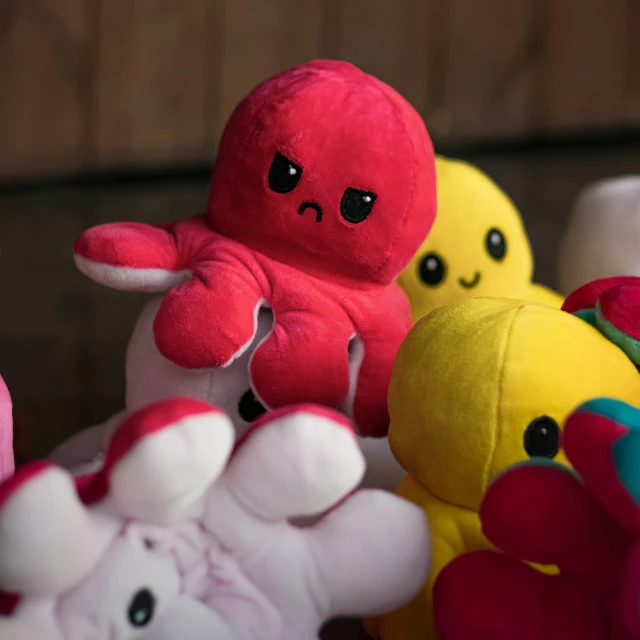 three different colored stuffed animals sitting in front of each other
