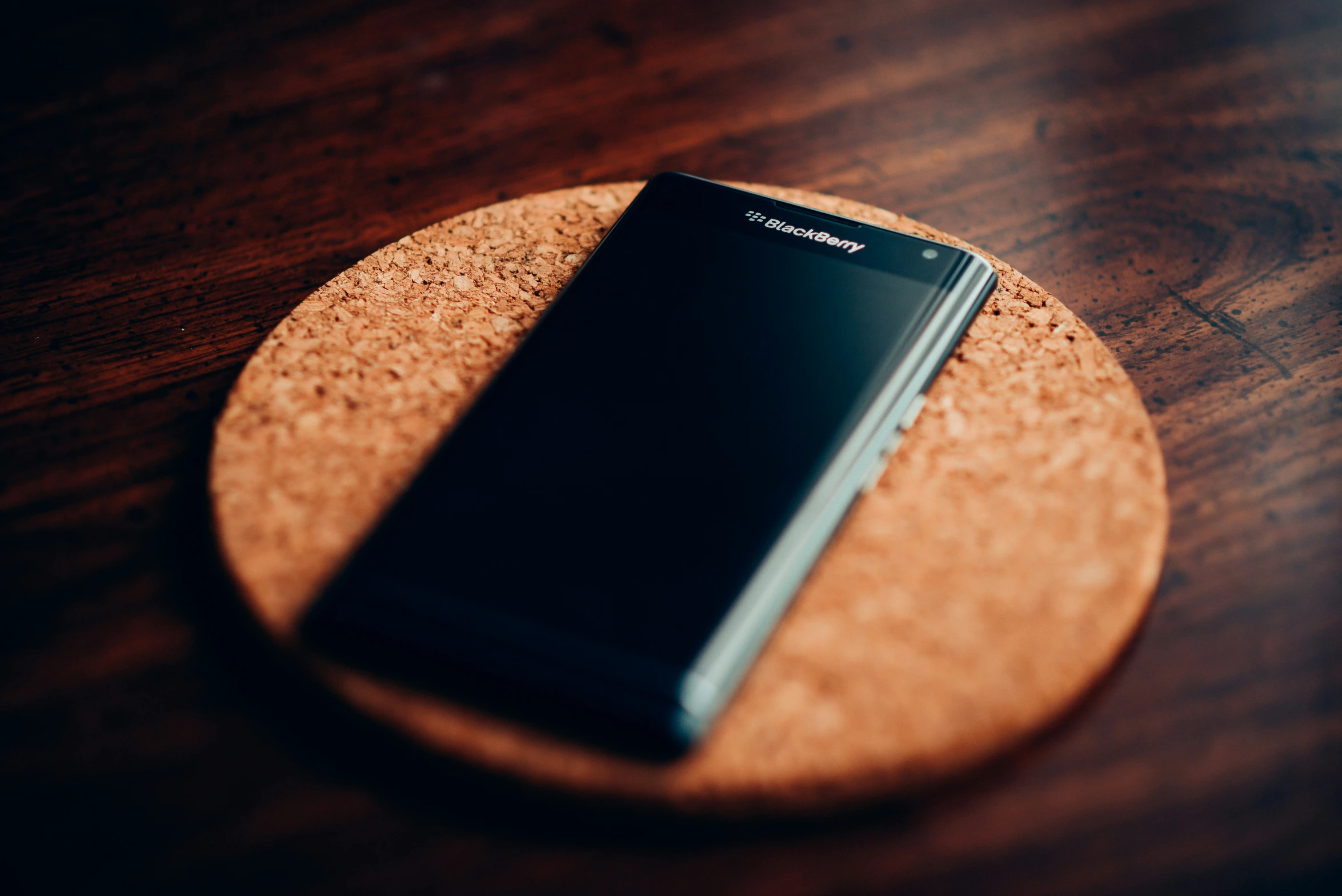 a black cell phone resting on a round cork coaster