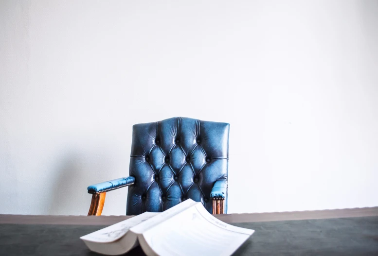 a blue chair sitting next to an open book