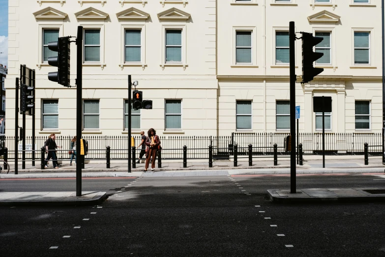 two people waiting at a traffic light in front of a tall building