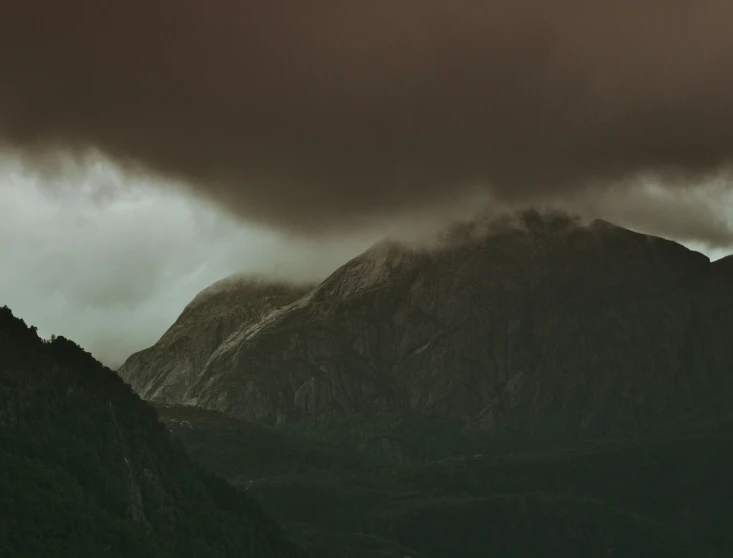 this is a dark mountain with some clouds rolling through it