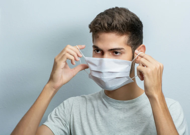 the boy in the t - shirt is wearing a surgical mask to cover his ears