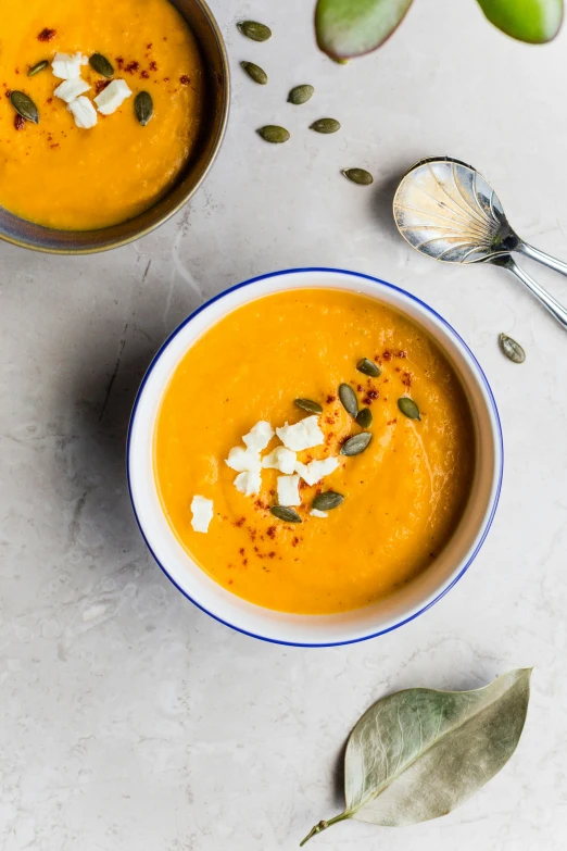 the two bowls are filled with soup, some with bread crumbs