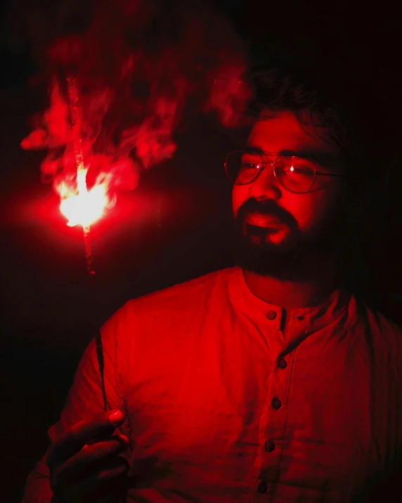 a man in a red shirt is holding a lit cigarette