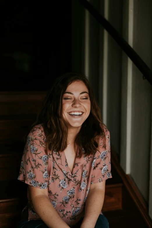 a smiling woman sits on a wooden floor