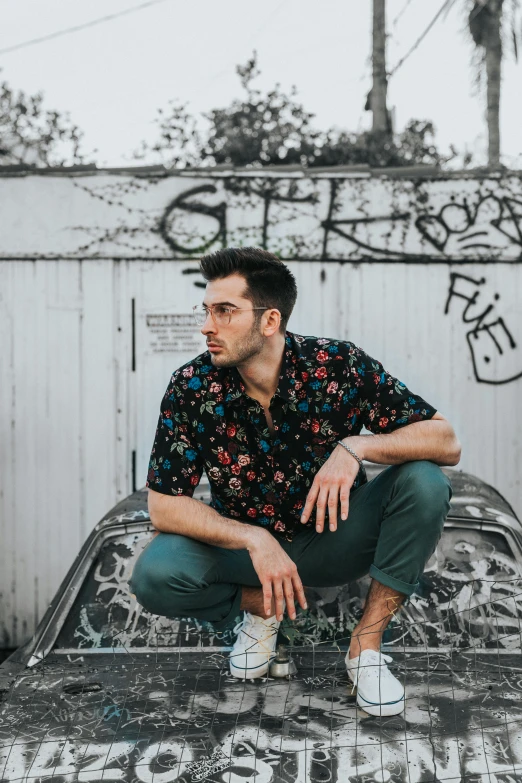 a man in green pants and white shoes sitting on an old car