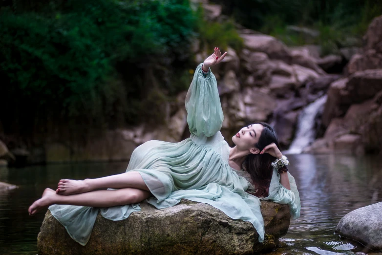 a woman laying on a rock on top of a river