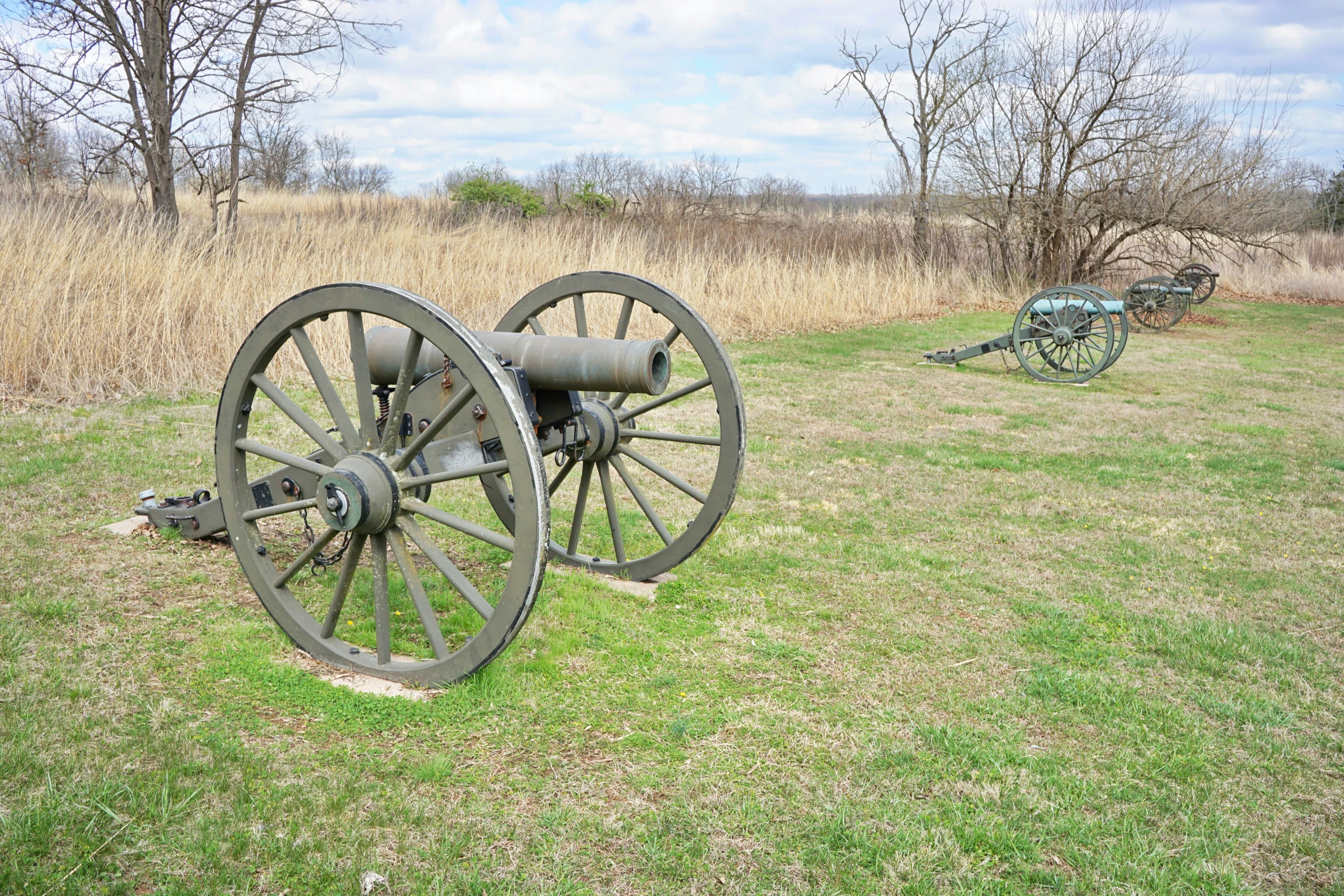 two war cannon wheels on display in an open field