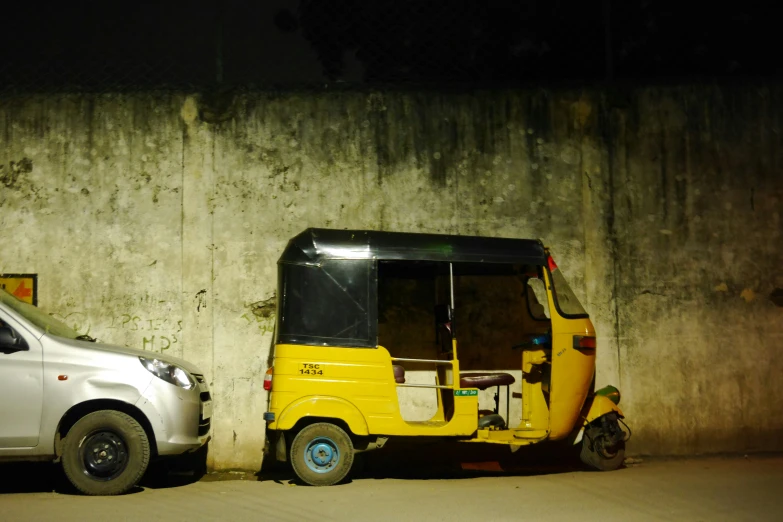 a small yellow truck parked next to a white car