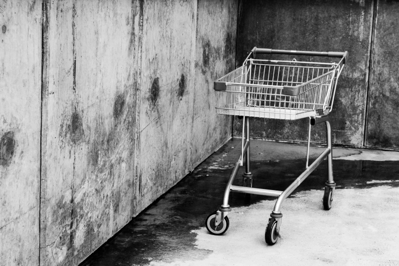 black and white po of a shopping cart in front of a cement wall