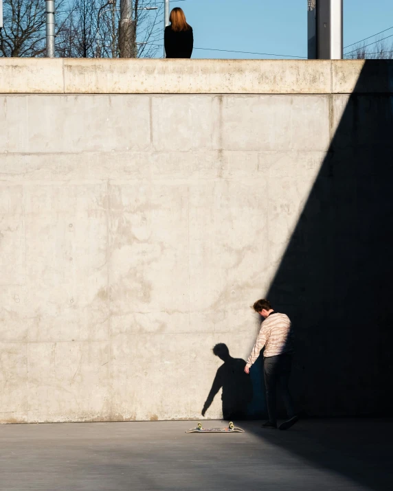 two boys riding skateboards against a concrete wall