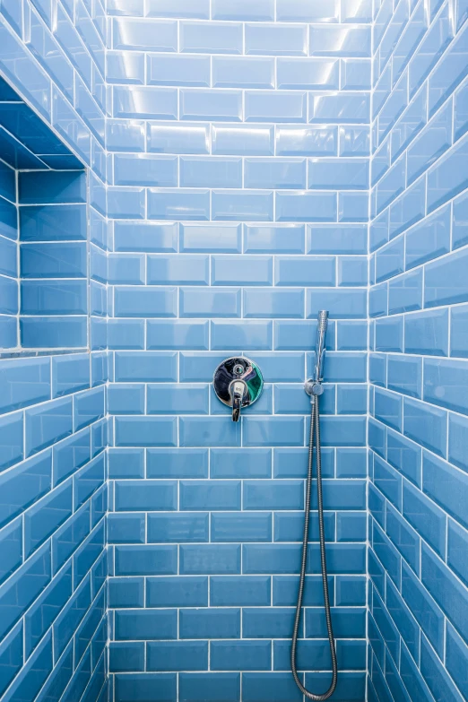 a blue tiled bathroom shower with overhead sprayer