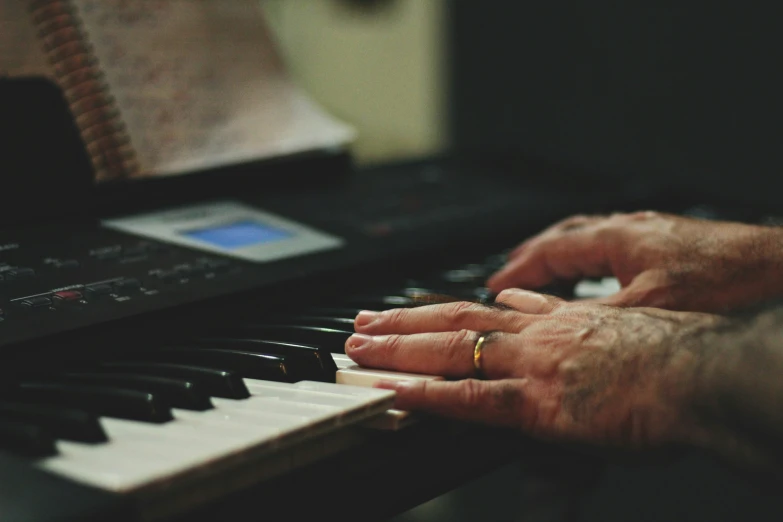 an older man playing the piano with a ring on his finger