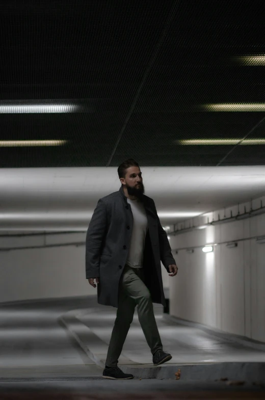 a man with a coat walks down the corridor