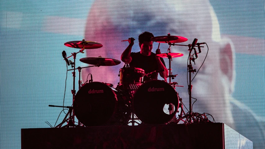 the silhouette of a drummer on stage is lit up