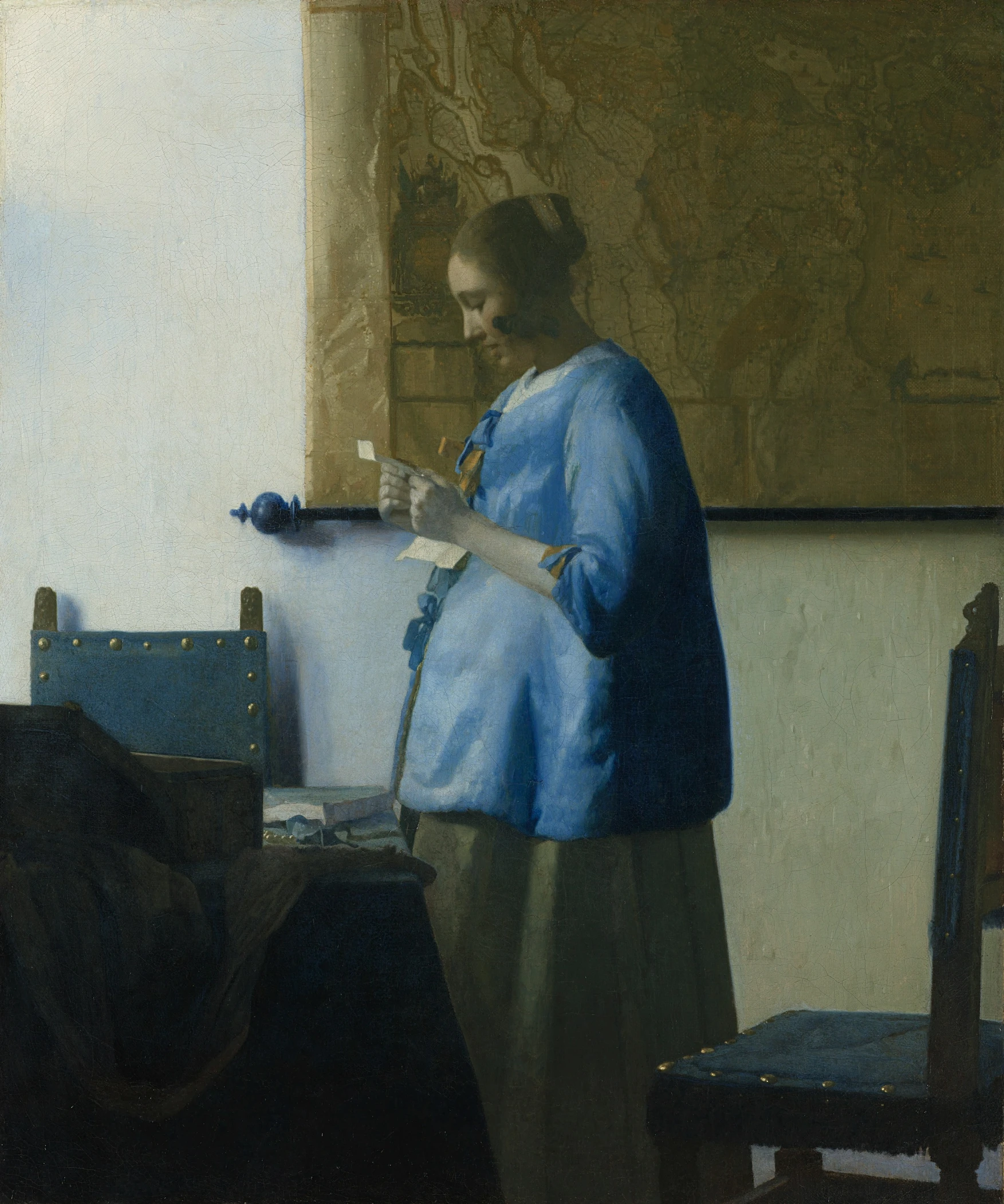 a woman holding soing over a painting that she is looking at