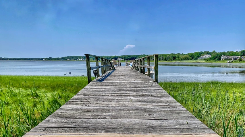 a wood pier that looks out over a grassy field