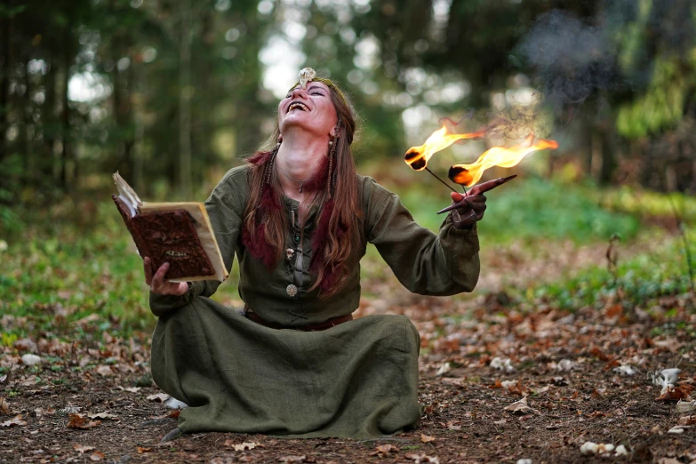 a woman sitting in the woods holding fire