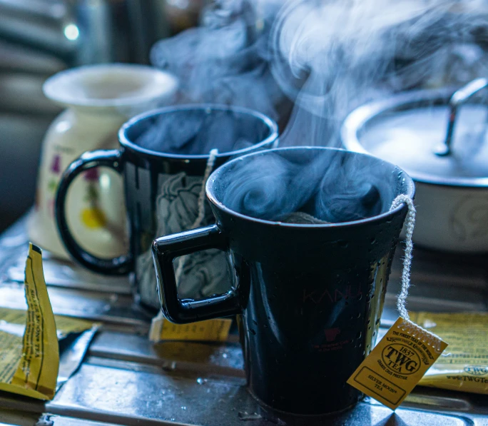 two mugs of steaming , one filled with water and one empty