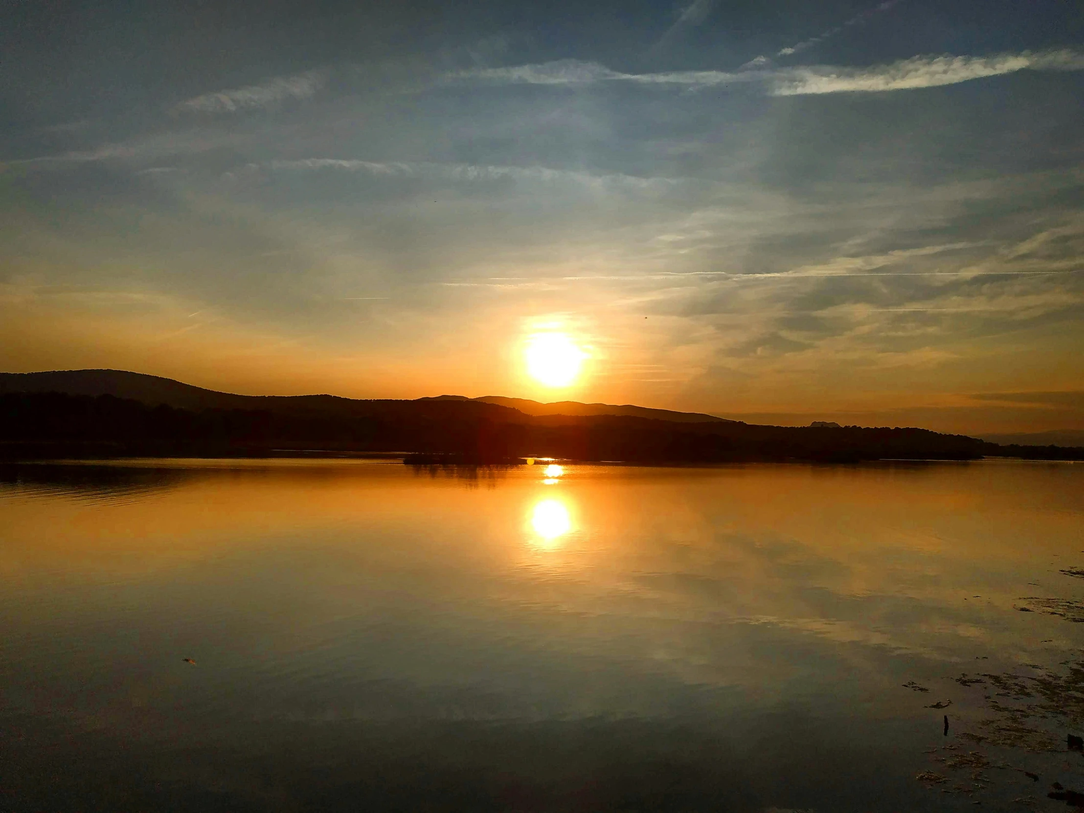 a bright sunset over a calm lake in the evening