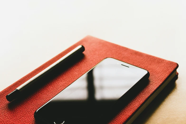 an iphone sitting on top of a red folder