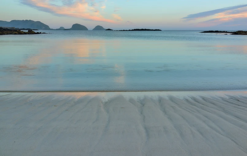 the sun is setting at a beach that looks over the water