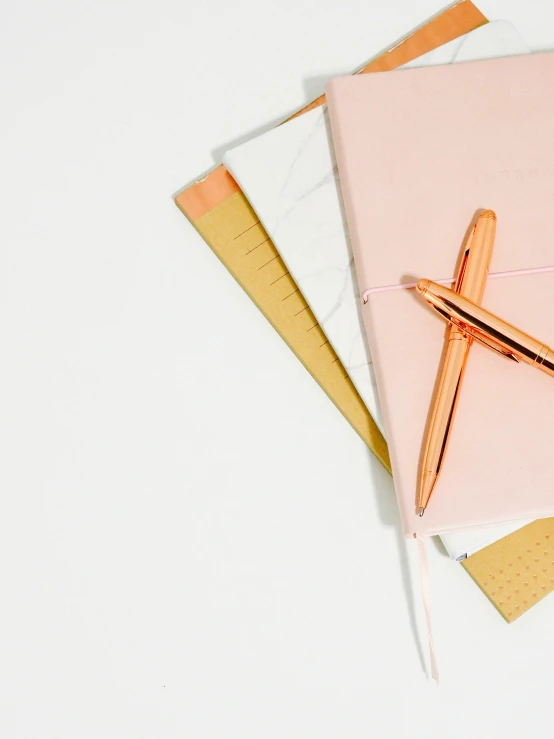 a pink and gold note pad with gold pen on it