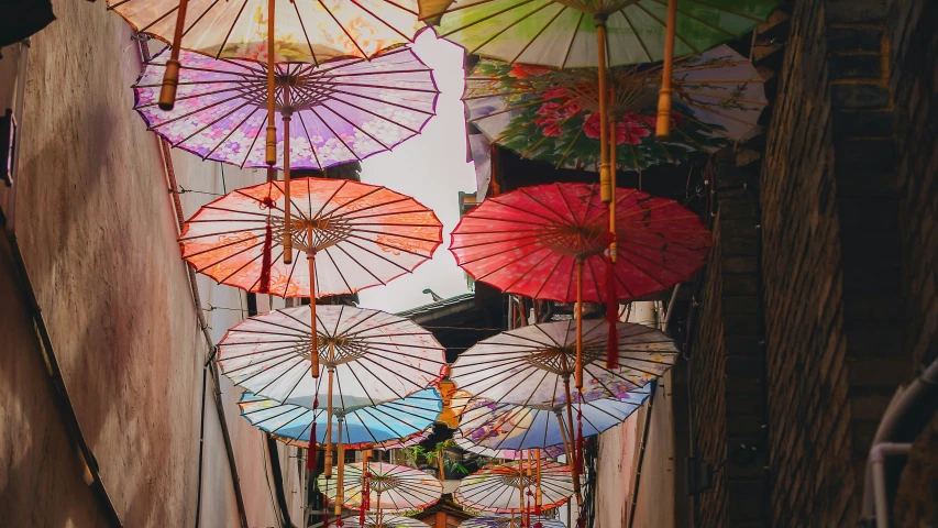 a group of colorful umbrellas hanging from the side of buildings