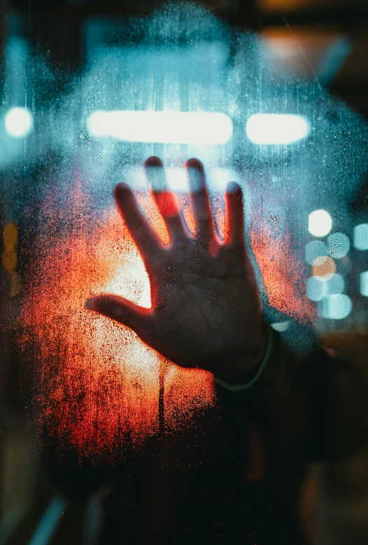 a hand reaching out of a window with a blurry image behind it