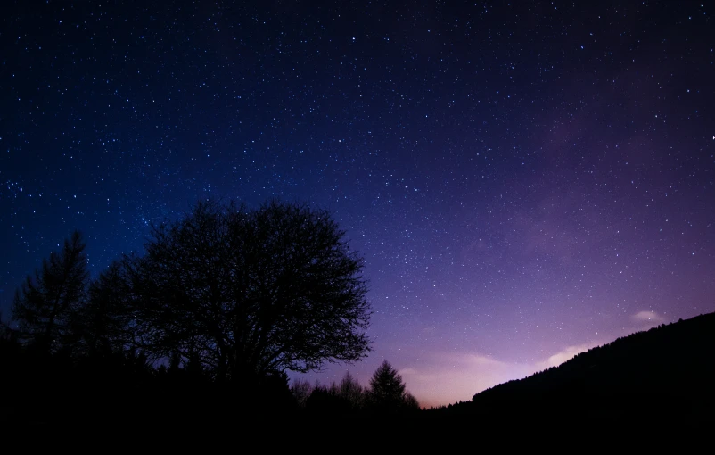 the night sky with stars above a mountain