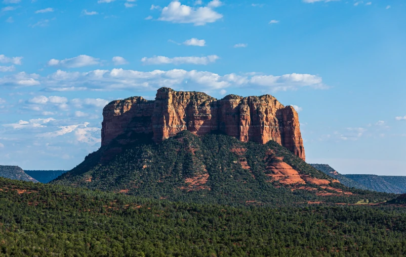 several tall red rocks on a hillside