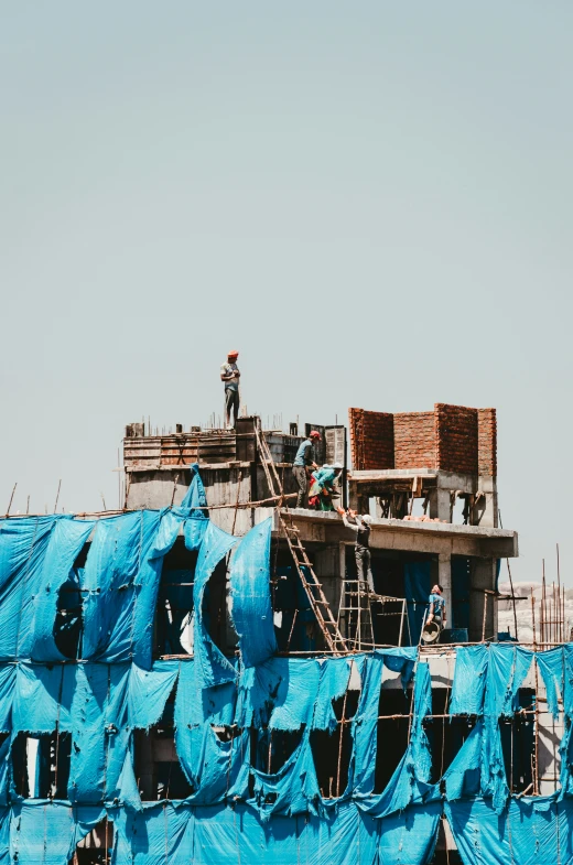 a tall blue building with a crane standing over the top