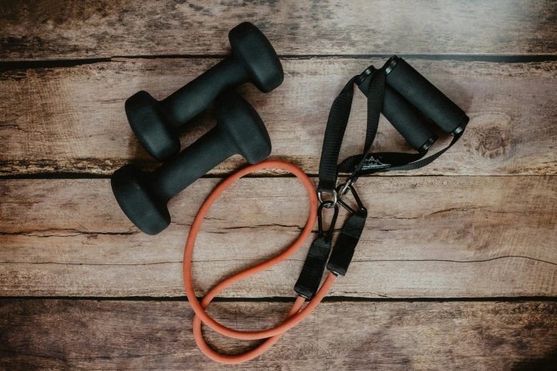 the gym equipment on the wooden floor has straps that hold up two dumbbells