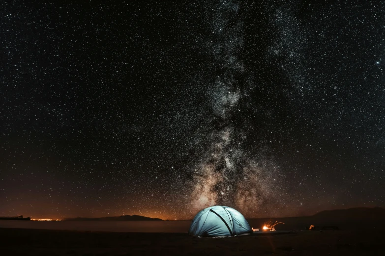 an illuminated tent set up in a field at night