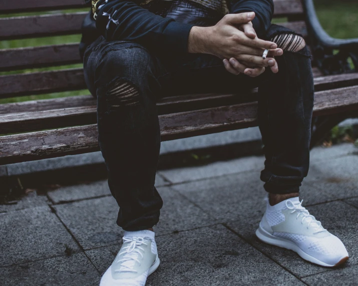 a man sitting on a bench in white sneakers