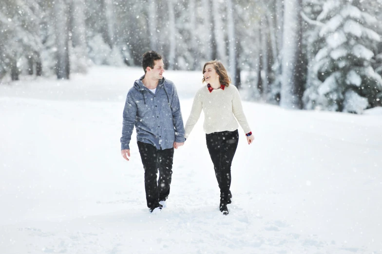 couple walking through the snow carrying each other in their hands